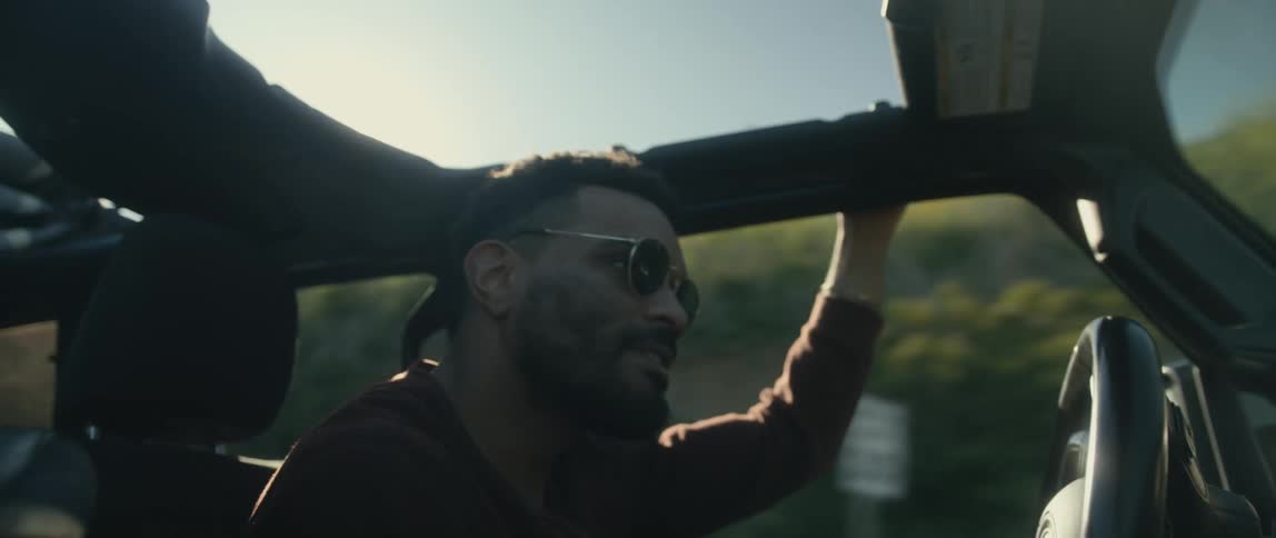 A man is driving his car in a rural area at dusk