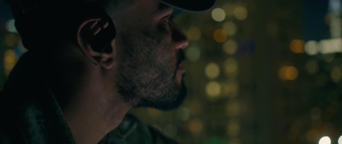 A man outside looks up at the lit up city skyline