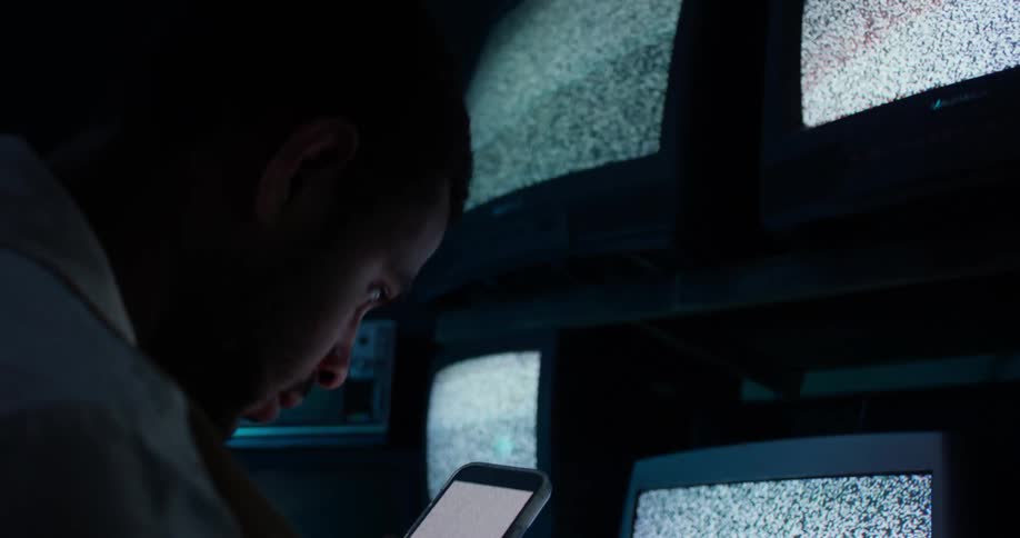 Young teenage boy is looking at his phone in front of the television