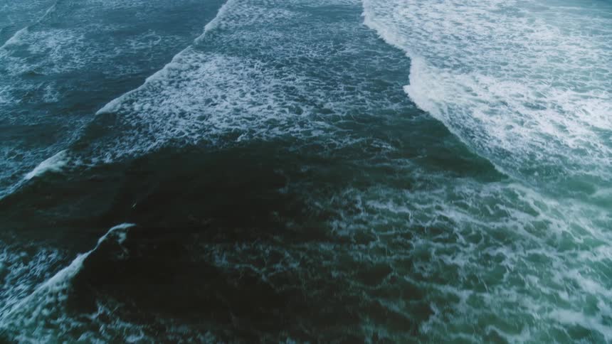 Aerial view of ocean waves breaking against a beach