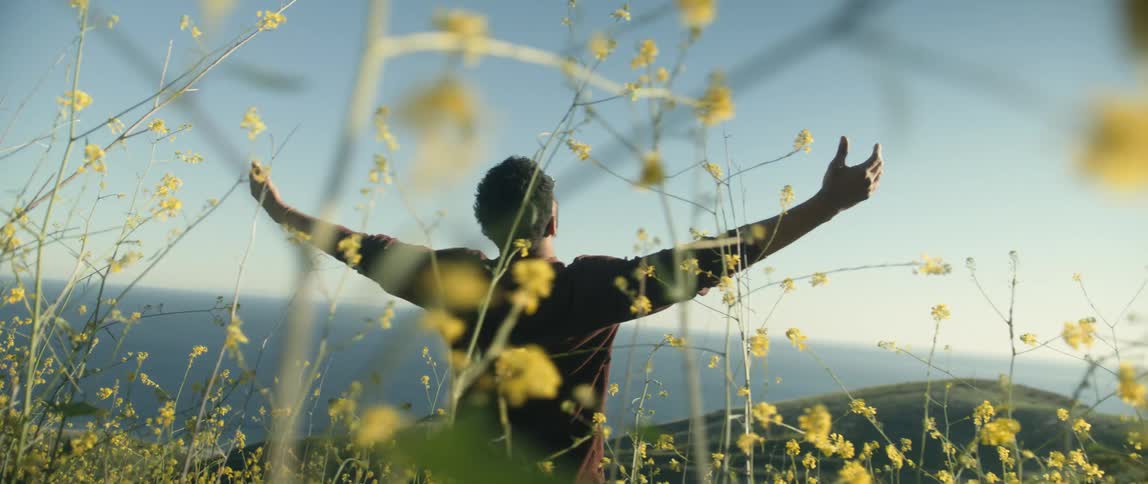A man reaches his hands up on the hill