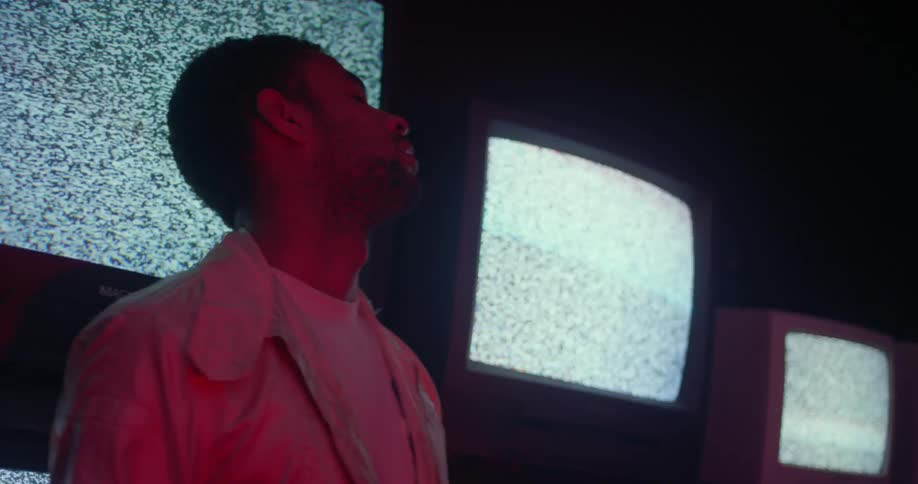 An employee with his eyes closed stands in front of a display of televisions with fuzzy screens