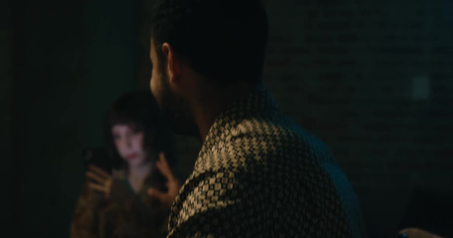 A man at the head of a table talks as the women at the table look at their phones