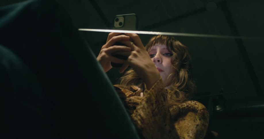 A woman is sitting on a chair and texting on a cellphone