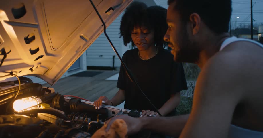 Man and woman are talking while they fix a car together