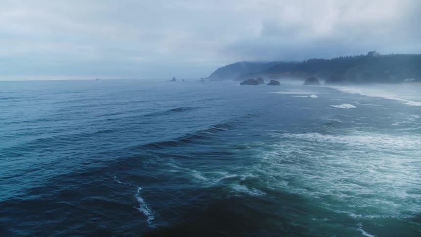 Aerial views of waves crashing against a pacific ocean beach