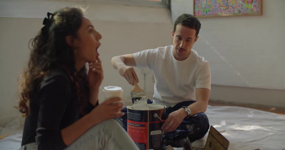 Young man and woman are sitting down by some paint