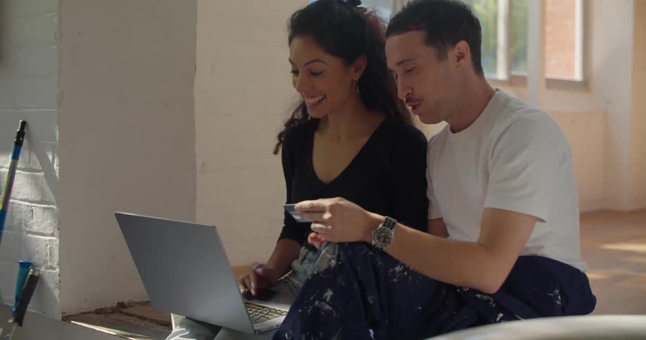 Man and woman are sitting on the floor next to the laptop