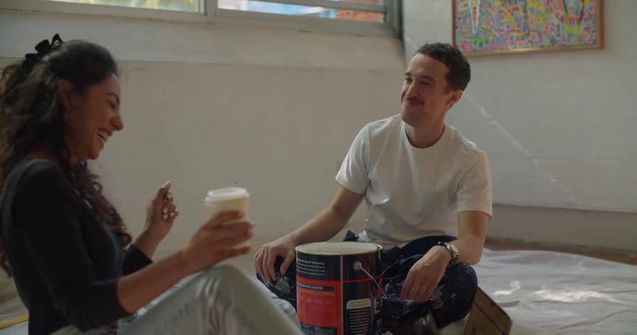 Young woman and man are sitting down by some paint