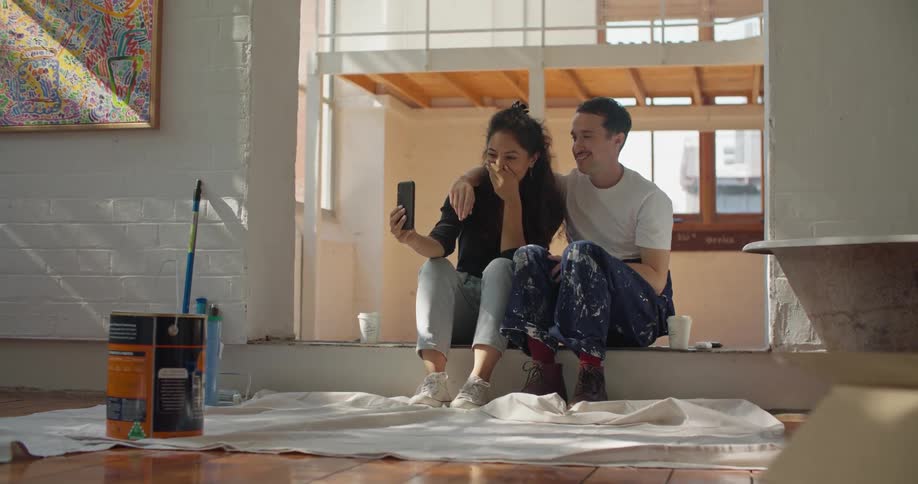 A couple takes a break from painting to sit and talk on a video call