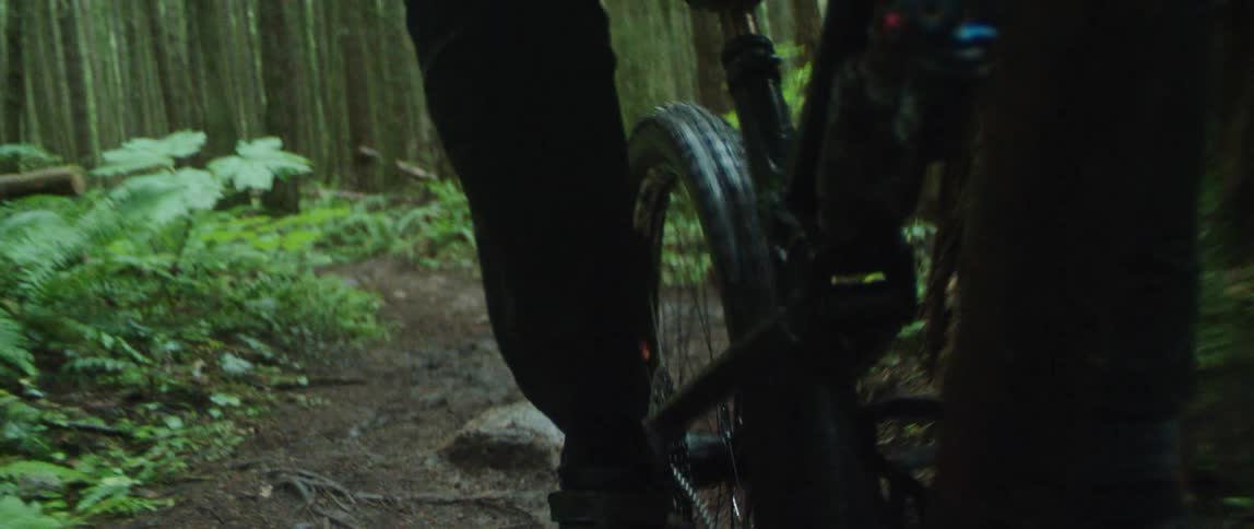 A person is biking through a muddy forest trail