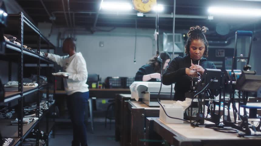 Coworkers work machines and check inventory in fabric print shop