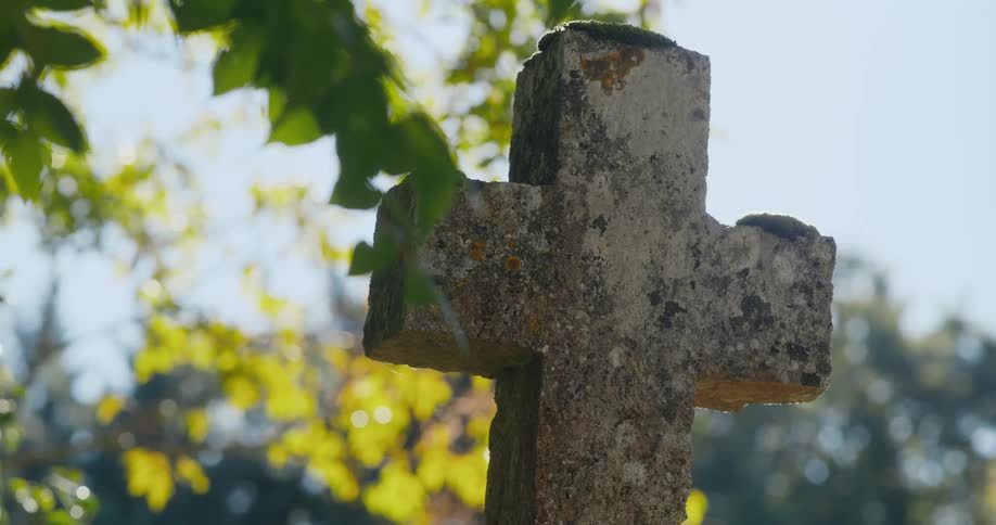 Concrete cross on a grave in a cemetery at daytime