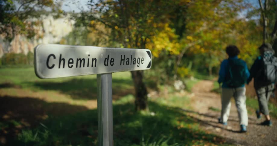 A sign next to a gravel travel through a field during the day