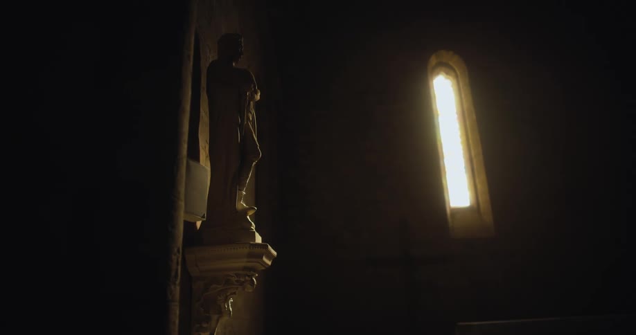 Statue over a pedestal on the wall of a dimly lit church