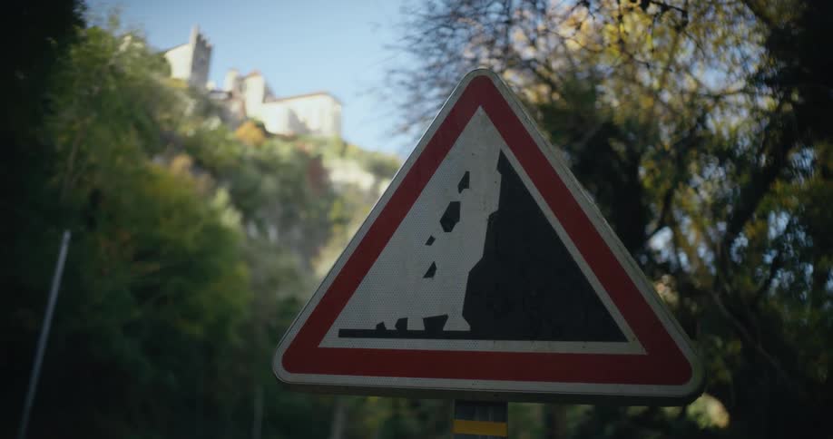 There is a sign in the outdoors and buildings are in the distance