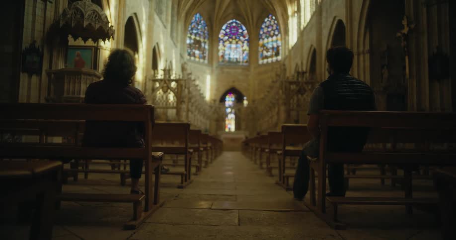 A man and woman sit in the back of an empty church