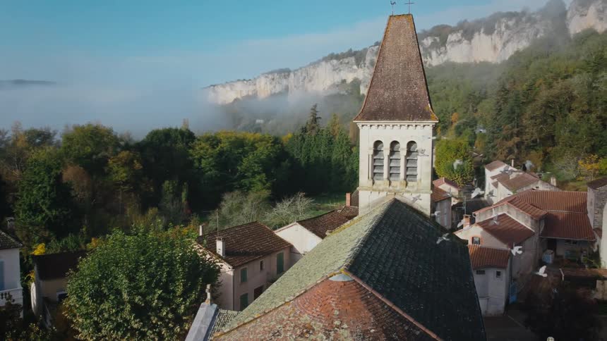 A tower on a building looms over the surrounding buildings in a small rural town during the day