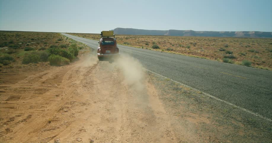 A car at the side of the road starts to drive and merges on to the road