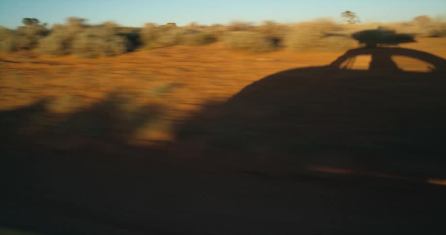 The shadow of a car driving through the wilderness