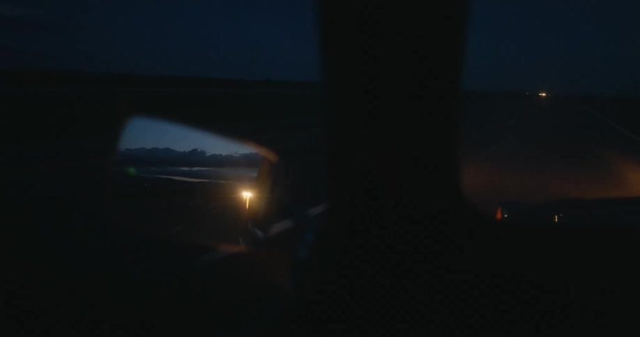 A vehicle drives closely behind another car on the highway at night