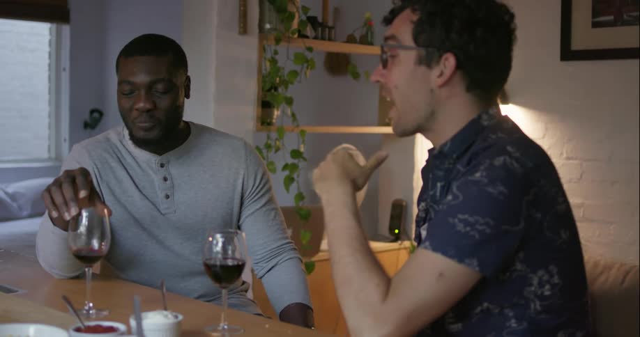 Two men laugh and talk while drinking red wine