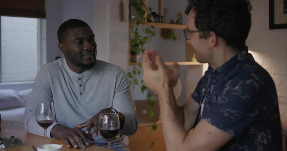 Two men talk and laugh at a table