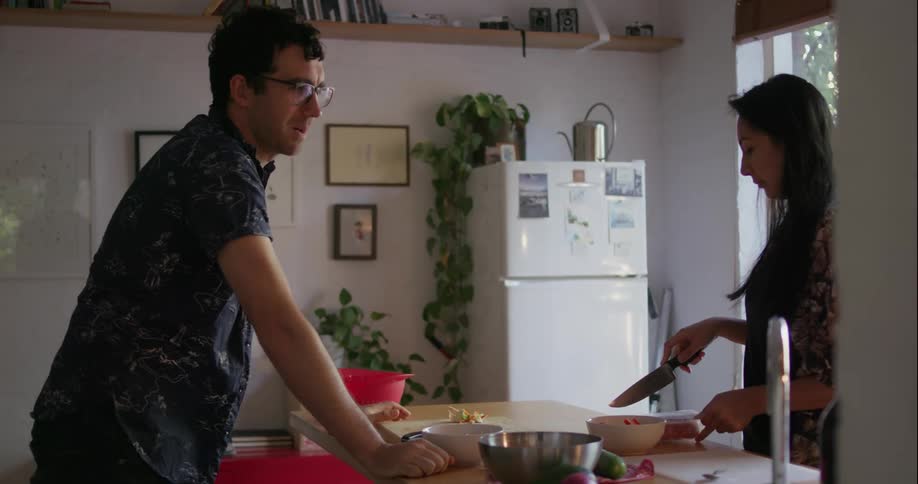 Man and woman cook dinner and talk together