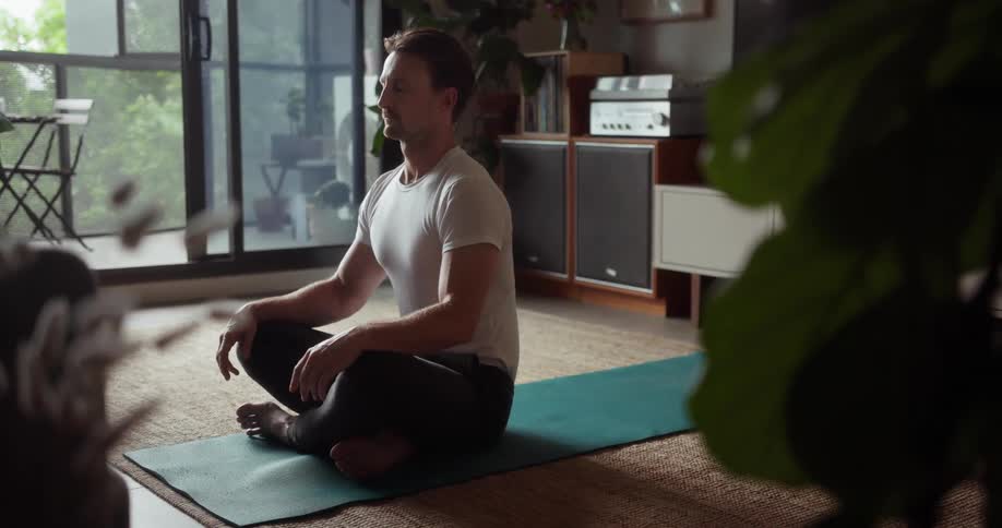 A man is meditating in the living room