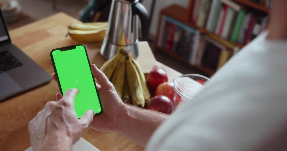 A man is using his phone in the kitchen