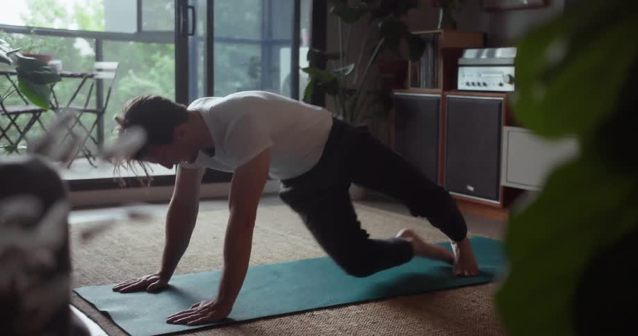 A man does yoga inside a living room