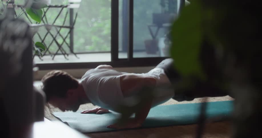 Man does push ups on a mat in a small room