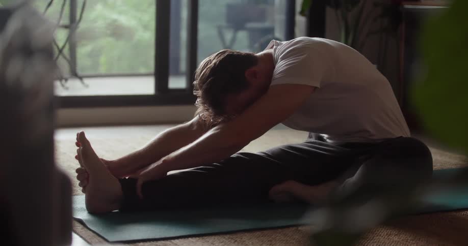 A man stretches on a yoga mat at home