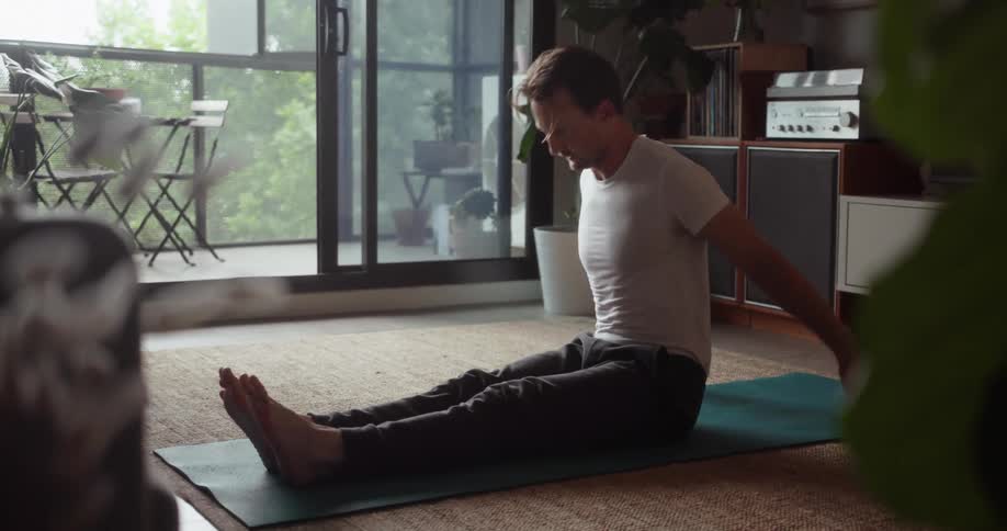 A man does yoga inside a living room