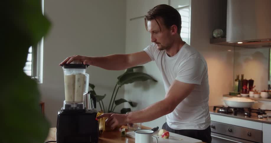 A man uses a blender in the kitchen