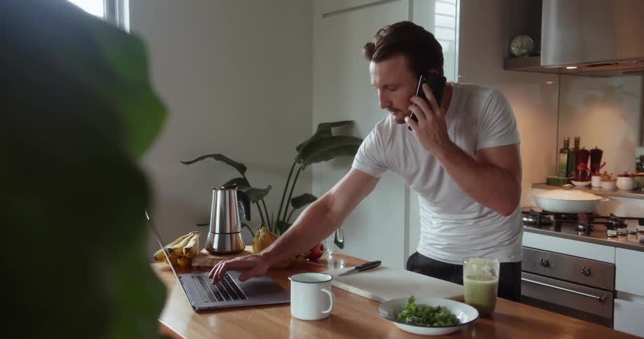 A man drinks a green smoothie and talks on the phone