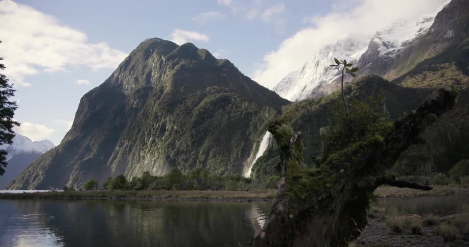 A waterfall pours into the lake near a mountain