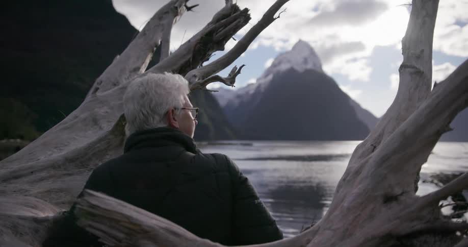Woman stands outside looking across a lake