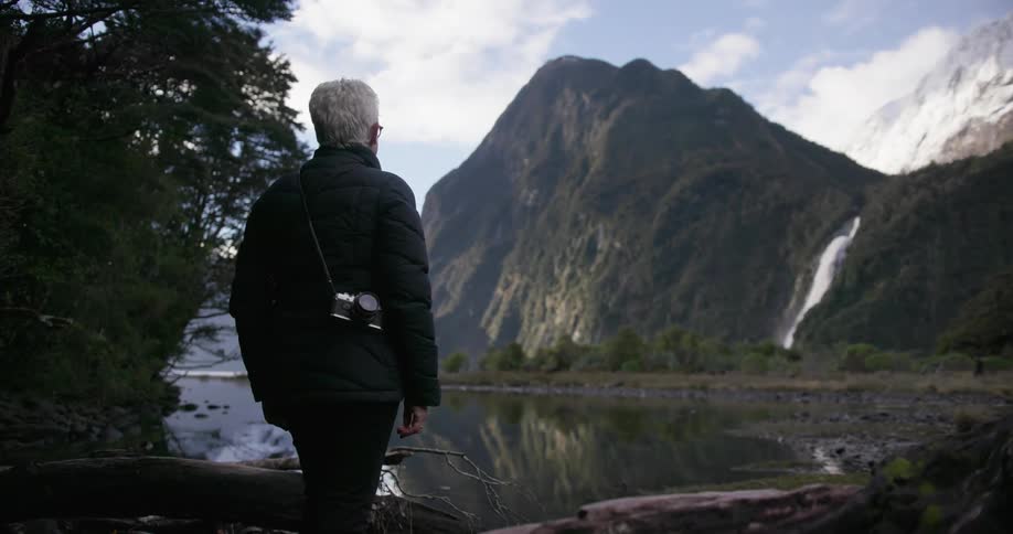 A woman carrying a camera looks around at nature