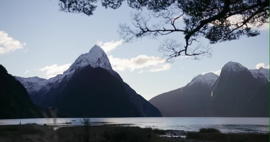The sunshine glistens off the lake below a mountain