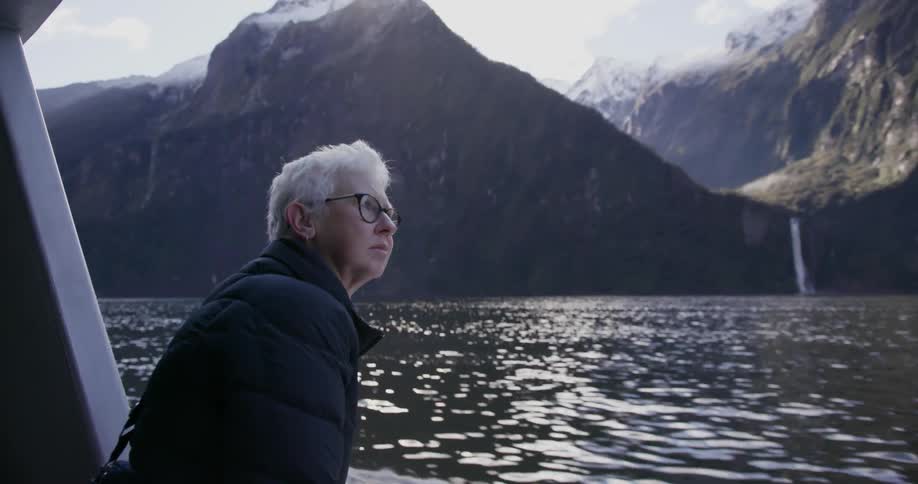 A woman leans over the side of a boat as it travels