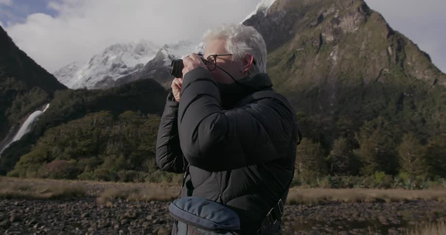 A woman takes a photograph near mountains