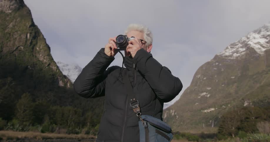 A person takes pictures near mountains