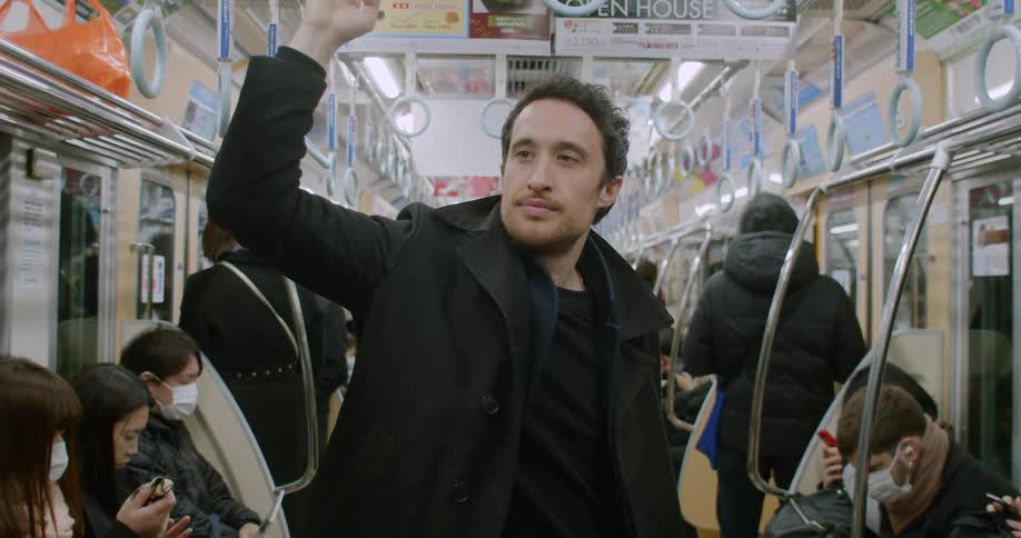 Man using pivoted grab handles stands on a subway train