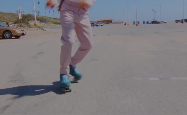 A man wearing a pink jacket and pants is roller skating on a parking lot