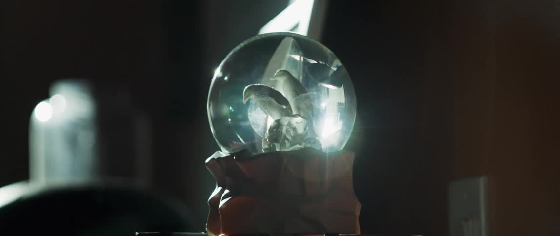 A snow globe featuring a family of penguins sits on a tabletop