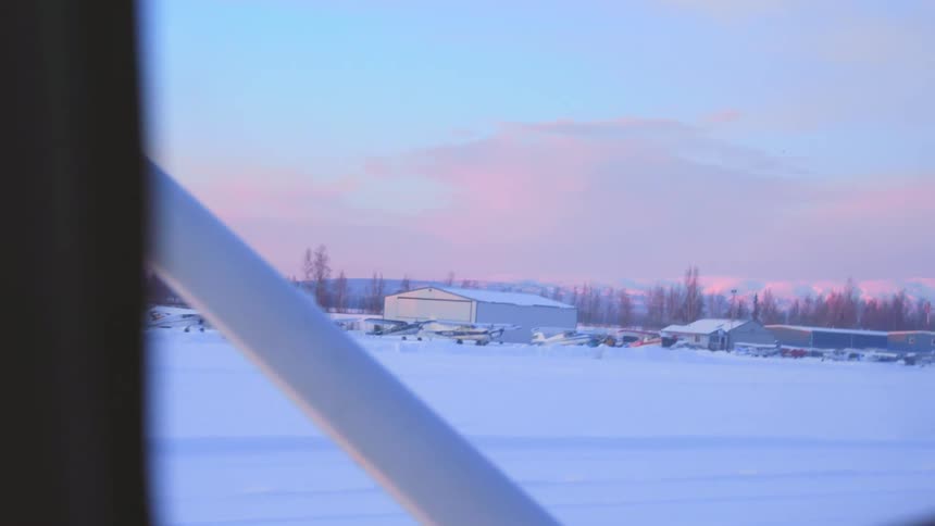 A view from an airplane of airplanes parked in a snowy lot