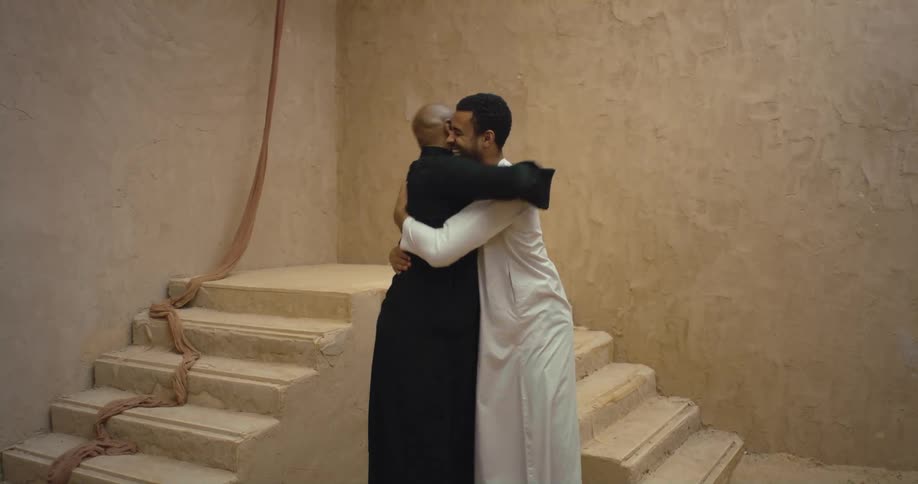 Two men hug and talk