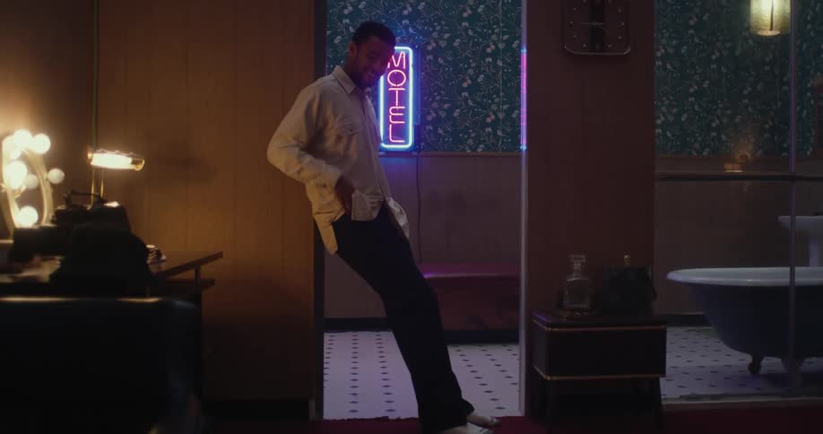 A man is standing inthe doorway of a bathroom in a dark room