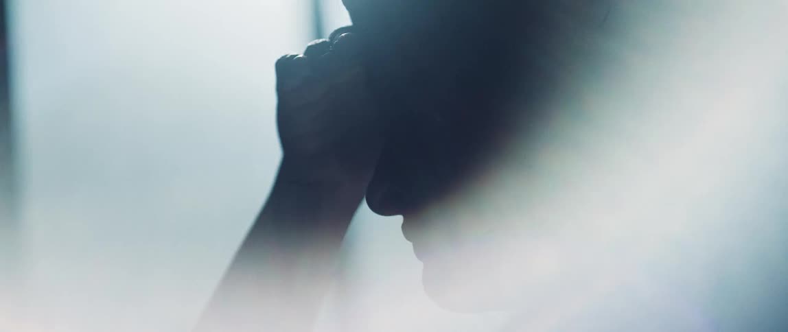 Upset womans head and hand is silhouetted against the office window